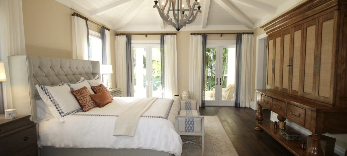 A large bedroom with neutral tones and a wooden cabinet