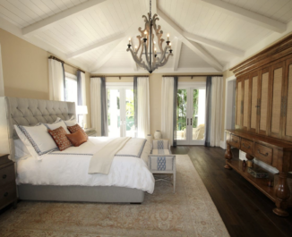 A large bedroom with neutral tones and a wooden cabinet