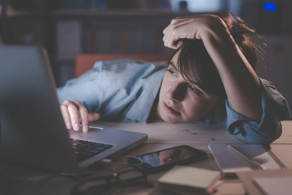 Sleepy woman working with her laptop. Sleep Can Help You Keep Your Job.